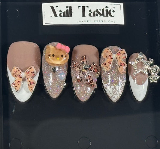 Decorative false nails with butterflies and a Hello Kitty design on a black background with 'Nail Tastic' branding.